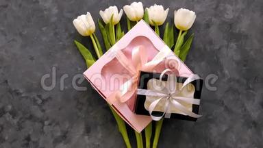 白色郁金香花，黑色和粉红色的礼品盒在黑暗的背景平躺。 4K<strong>视频</strong>。 三月8<strong>母亲节</strong>快乐